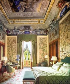 an ornate bedroom with green and gold walls, carpeted flooring and paintings on the ceiling