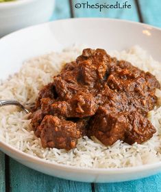 a white bowl filled with rice and meat on top of a blue wooden tablecloth