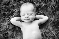 a black and white photo of a baby laying on his back with its eyes closed