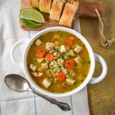 a white bowl filled with soup next to sliced bread on top of a wooden cutting board