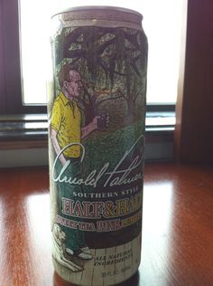 a can of beer sitting on top of a wooden table next to a windowsill