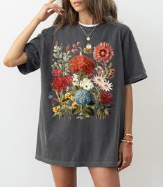 "Boho Wildflowers Cottagecore Shirt: Embrace the charm of the countryside with our Boho Wildflowers Cottagecore Shirt. This beautifully designed shirt features delicate wildflower prints, perfect for those who love the cottagecore aesthetic. It's an ideal piece for casual wear, bringing a touch of rustic elegance to your wardrobe. Gift For Her: Looking for the perfect gift? Our floral shirts make an excellent choice for the special women in your life. Whether it's for a birthday, anniversary, or Vintage Relaxed Fit Shirt With Plant Print, Cottagecore Style Shirt With Graphic Print, Cottagecore Shirt With Graphic Print And Relaxed Fit, Cottagecore Relaxed Fit Shirt With Graphic Print, Cottagecore Relaxed Fit Graphic Print Shirt, Bohemian Floral Print Relaxed Fit Shirt, Bohemian Relaxed Fit Floral Print Shirt, Bohemian Relaxed Fit Floral Shirt, Bohemian Floral Print Shirt With Relaxed Fit