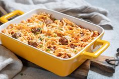 a yellow casserole dish filled with pasta and meatballs