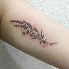 a flower tattoo on the left arm is shown in black and grey ink, with small flowers