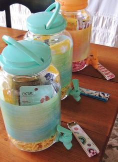 three jars with lids are sitting on a table next to scissors and toothbrushes