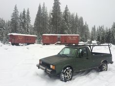 a truck is parked in the snow next to some red cabooses and trees