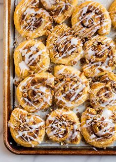 cinnamon rolls on a baking sheet with icing drizzled over them