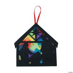 a paper house ornament hanging from a red ribbon on a white background with colorful shapes