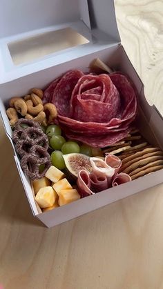 a box filled with meat, cheese and crackers on top of a wooden table