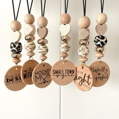 several wooden necklaces hanging from hooks on a white wall with black and white designs