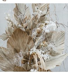 an arrangement of dried flowers and leaves in a vase