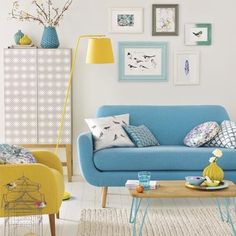 a living room filled with furniture and pictures on the wall next to a table in front of a blue couch