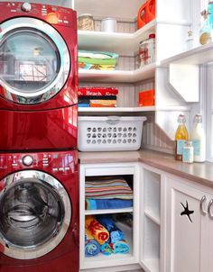 a red washer and dryer in a white kitchen with open shelve