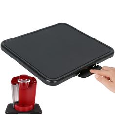 a person is holding the lid on a red blender and it's attached to a black tray