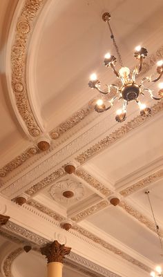 a chandelier hangs from the ceiling in an ornately decorated room with columns