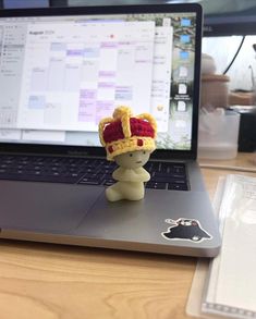 a small figurine is sitting on top of a laptop computer's keyboard