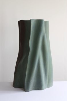 a green vase sitting on top of a white table