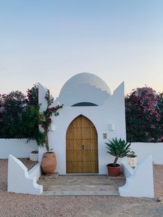 a white building with a wooden door and two planters