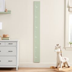 a wooden giraffe sitting next to a white dresser in a child's room