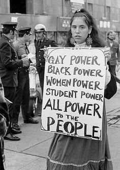 a woman holding a sign that says gay power, black power, women power, student power, all power to the people