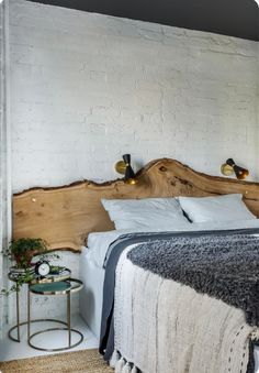 a bed that is made up with blankets and pillows on top of the headboard