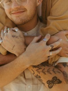 a man with tattoos on his arm hugging another man