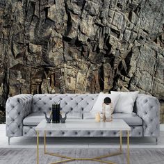 a couch and table in front of a large rock wallpapered room with wood flooring