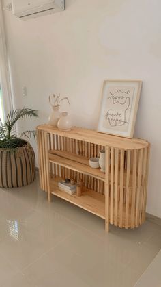 a wooden shelf sitting next to a potted plant on top of a hard wood floor