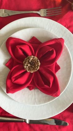 a white plate topped with a red flower next to silverware and utensils