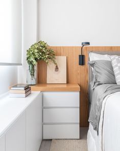 a bedroom with a bed, nightstand and plant on the end table next to it