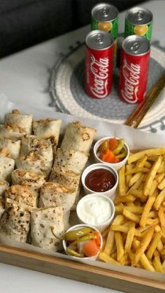 a tray filled with food next to two cans of soda and french fries on a table