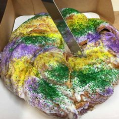 a person cutting into a cake covered in sprinkles with a large knife