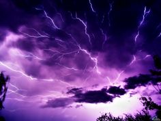 the sky is filled with purple lightning and it appears to be very dark in color