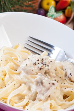 a white bowl filled with pasta covered in gravy and topped with a fork