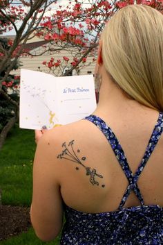 a woman with a tattoo on her back holding a book