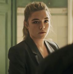 a woman sitting in front of a mirror looking at the camera with an intense look on her face