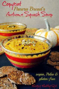 two bowls filled with food sitting on top of a table next to crackers and pumpkins