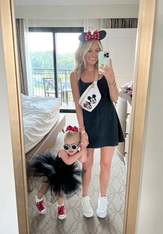 a woman taking a selfie with her daughter wearing minnie mouse ears and mickey ears