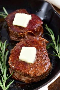 two steaks in a skillet with butter and rosemary on the side for garnish