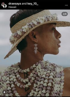 a woman wearing a large hat with flowers on it's neck and necklaces around her neck