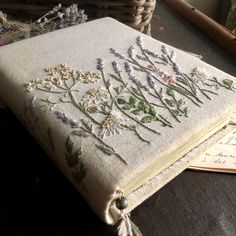 an old book with flowers on it sitting on a table next to some other items