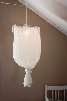 a white light hanging from the ceiling in a room with a crib and bed