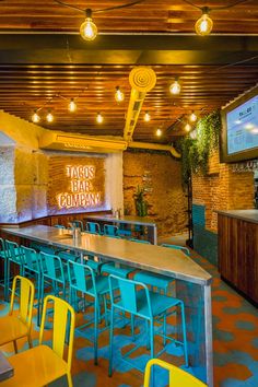 the inside of a restaurant with tables, chairs and televisions hanging from the ceiling