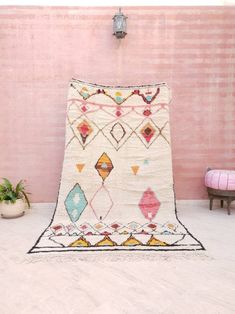 a pink wall with a rug on the floor