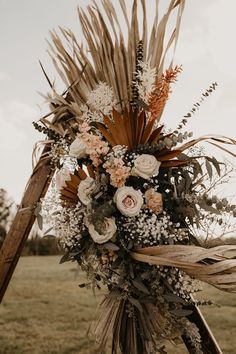 an arrangement of dried flowers and foliage on a wooden pole