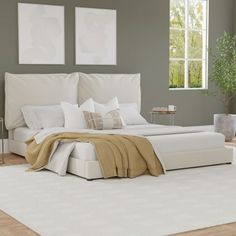 a white bed sitting in a bedroom on top of a hard wood floor next to a window