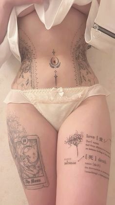 a woman with tattoos on her stomach is wearing a white panties and holding a cell phone