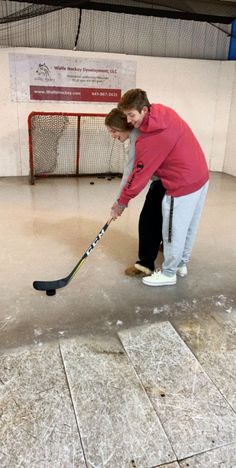 a woman is playing hockey in an indoor rink with ice and snow on the floor