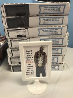 a stack of pizza boxes sitting on top of a table next to a framed photo