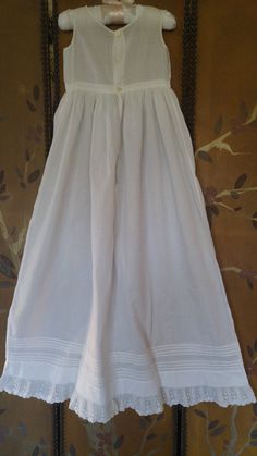 "50s gorgeous white cotton long under dress for a Christening / Baptism. Sleeveless top with two tiny little pearly buttons at the back. Waistband with the long skirt flaring out from it. Bottom of skirt has little tiers of fabric and then a lovely cotton lace trim at the hem. across chest 19\" around, waist 19\" around, skirt length 30\", dress length total 37\"" Fitted Sleeveless Cotton Baptism Dress, Solid Color Summer Baptism Dress, Elegant White Petticoat For Daywear, Fitted Baptism Dress With Lace Trim For Daywear, Fitted Baptism Dress With Lace Trim, Vintage Fitted Baptism Dress For Summer, Cotton Baptism Dress With Lace Trim For Summer, Summer Cotton Baptism Dress, Summer Vintage Fitted Baptism Dress